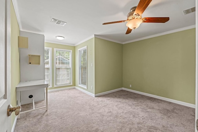 carpeted spare room with a ceiling fan, baseboards, crown molding, and visible vents