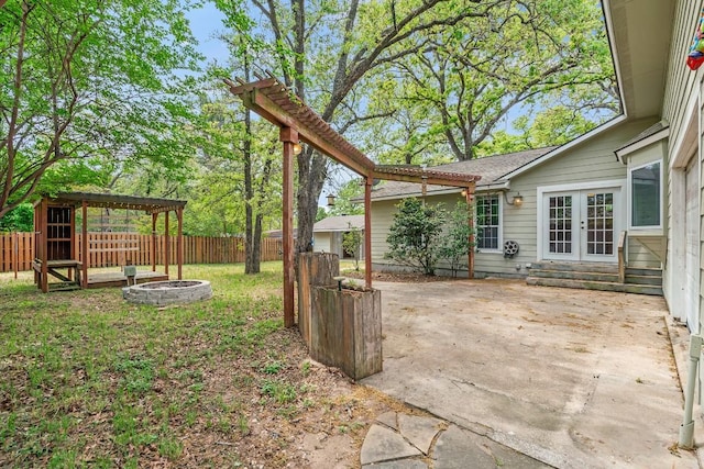 view of yard with a fire pit, french doors, a patio, and a fenced backyard