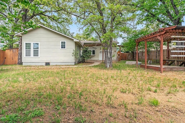 back of house with a lawn, a pergola, and fence