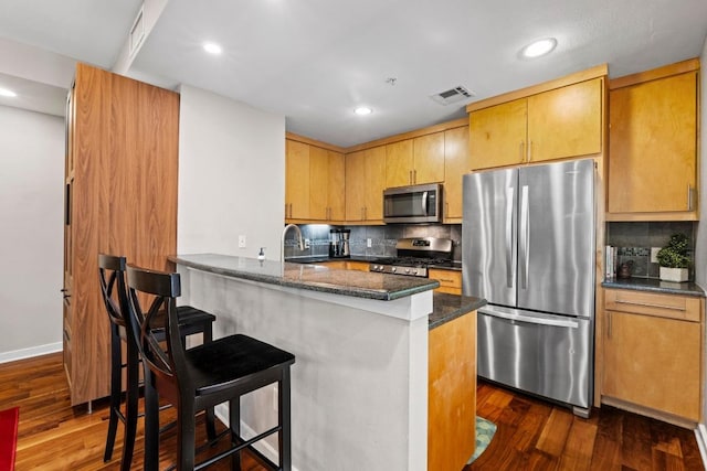 503 Swanee Dr Unit 11, Austin, TX 78752 - kitchen with stainless steel appliances, dark wood finished floors, backsplash, a breakfast bar area, and recessed lighting