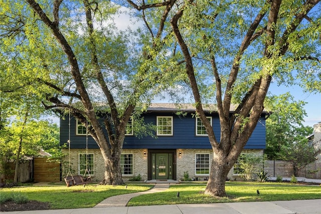 view of front of property with brick siding, a front yard, and fence