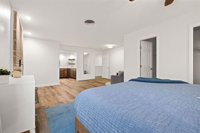 bedroom featuring a ceiling fan, light wood-style floors, baseboards, ensuite bath, and visible vents