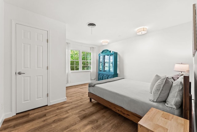 bedroom with wood finished floors, visible vents, and baseboards