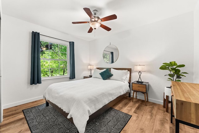bedroom with light wood-style flooring, baseboards, and ceiling fan