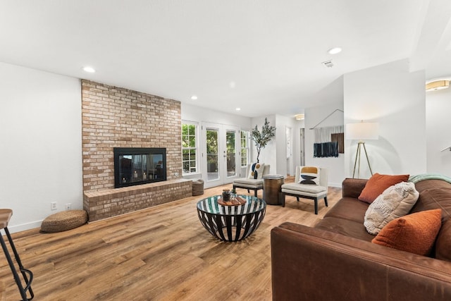 living area featuring recessed lighting, wood finished floors, a brick fireplace, and visible vents