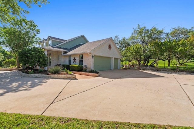 135 N Tumbleweed Trl, Austin, TX 78733 - view of property exterior featuring stone siding, concrete driveway, an attached garage, and a shingled roof