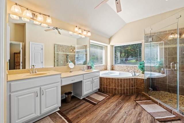 135 N Tumbleweed Trl, Austin, TX 78733 - bathroom featuring wood finished floors, double vanity, a bath, vaulted ceiling, and a stall shower