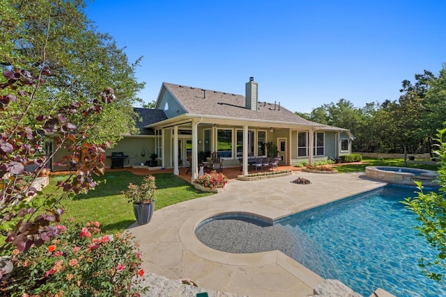 135 N Tumbleweed Trl, Austin, TX 78733 - rear view of property with a chimney, a patio, a pool with connected hot tub, a yard, and roof with shingles