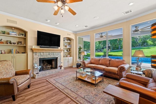 135 N Tumbleweed Trl, Austin, TX 78733 - living room featuring ceiling fan, built in shelves, ornamental molding, wood finished floors, and a fireplace