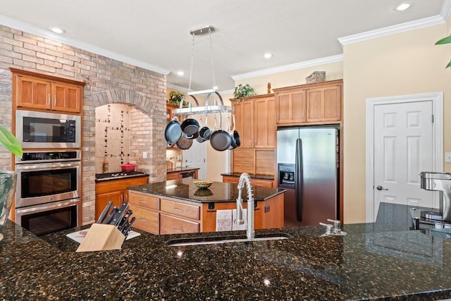 135 N Tumbleweed Trl, Austin, TX 78733 - kitchen with stainless steel appliances, a kitchen island, ornamental molding, dark stone counters, and arched walkways
