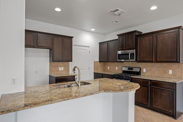 188 Rock Vista Run, Austin, TX 78737 - kitchen with appliances with stainless steel finishes, a sink, light stone countertops, dark brown cabinetry, and recessed lighting