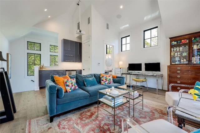 living room featuring light wood-style flooring, visible vents, high vaulted ceiling, and recessed lighting