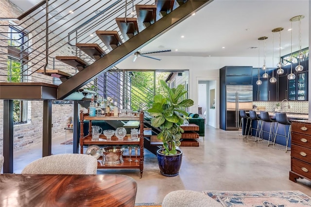 interior space with stairway, a high ceiling, backsplash, built in fridge, and finished concrete flooring