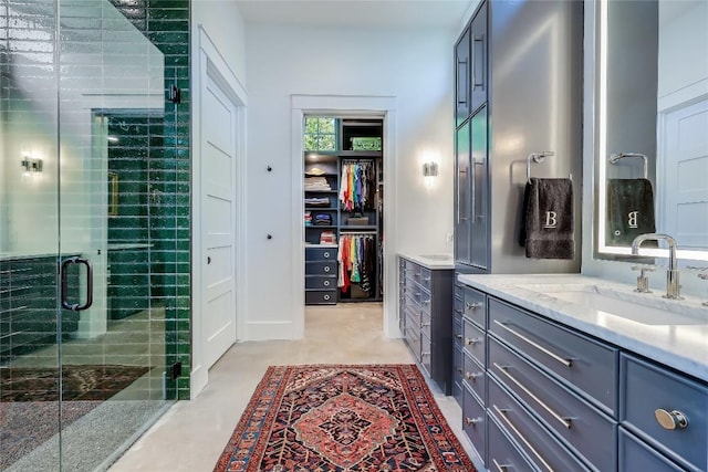 bathroom featuring a walk in closet, a shower stall, and vanity