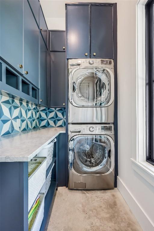 washroom with cabinet space and stacked washer / dryer