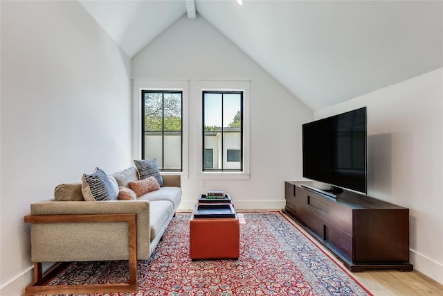living area with light wood finished floors, vaulted ceiling with beams, and baseboards