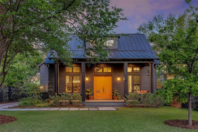 view of front of house featuring covered porch, a lawn, a standing seam roof, and metal roof