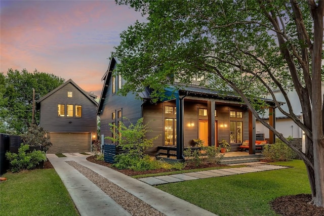 view of front facade featuring a garage, driveway, a porch, and a lawn