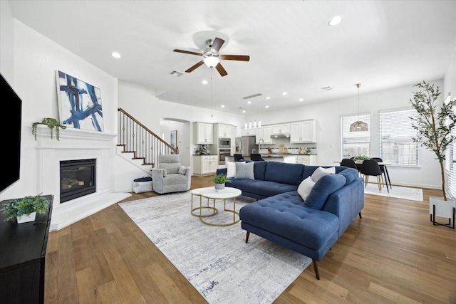 2216 Lookout Knoll Dr, Leander, TX 78641 - living area featuring a ceiling fan, a glass covered fireplace, wood finished floors, recessed lighting, and stairs