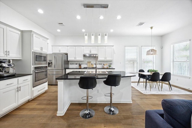 2216 Lookout Knoll Dr, Leander, TX 78641 - kitchen with appliances with stainless steel finishes, dark countertops, recessed lighting, dark wood-type flooring, and backsplash