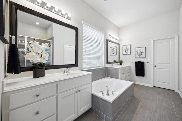 2216 Lookout Knoll Dr, Leander, TX 78641 - bathroom featuring two vanities, a bath, a shower stall, and baseboards