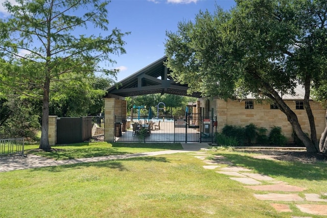 view of community with a gate, fence, playground community, and a yard