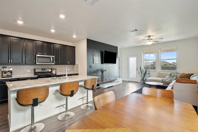 kitchen with stainless steel appliances, open floor plan, tasteful backsplash, dark wood finished floors, and recessed lighting