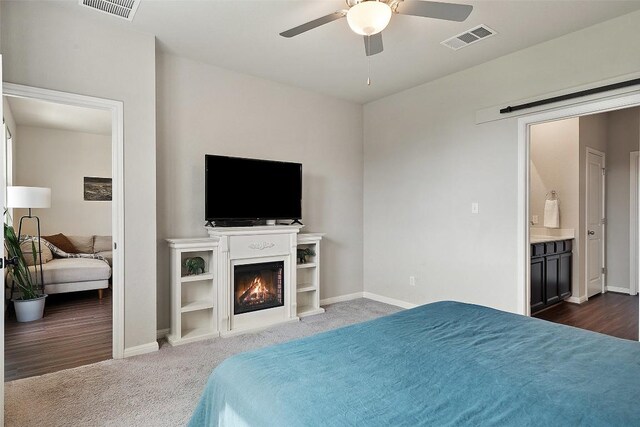 bedroom with baseboards, dark colored carpet, a warm lit fireplace, and a ceiling fan