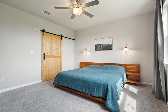 carpeted bedroom with a barn door, baseboards, and ceiling fan