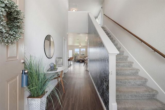 stairs featuring wood finished floors, a high ceiling, and ceiling fan
