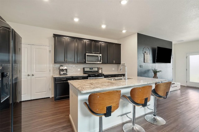 kitchen featuring stainless steel appliances, a sink, dark wood finished floors, backsplash, and recessed lighting