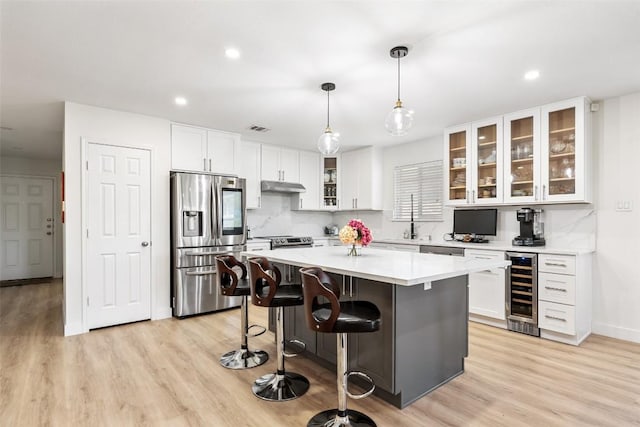11604 Gaelic Dr, Austin, TX 78754 - kitchen with appliances with stainless steel finishes, beverage cooler, under cabinet range hood, white cabinets, and a center island