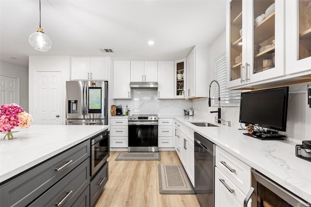 11604 Gaelic Dr, Austin, TX 78754 - kitchen with stainless steel appliances, under cabinet range hood, white cabinets, light wood-style floors, and backsplash