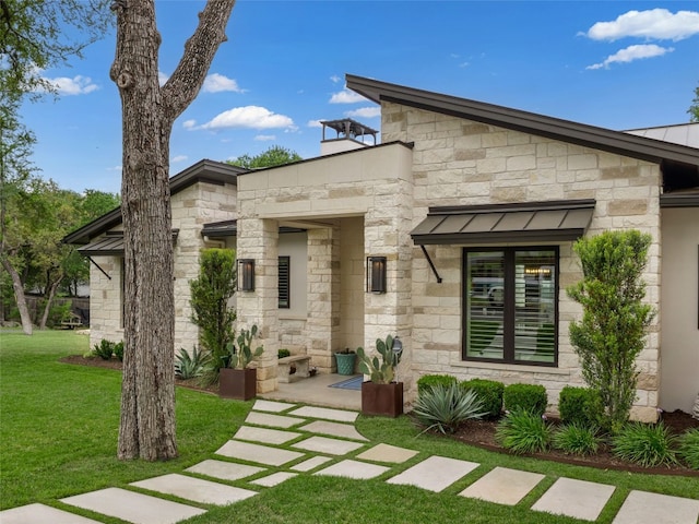 9806 Inca Ln, Austin, TX 78733 - view of front of house with stone siding, a front lawn, a standing seam roof, and a metal roof
