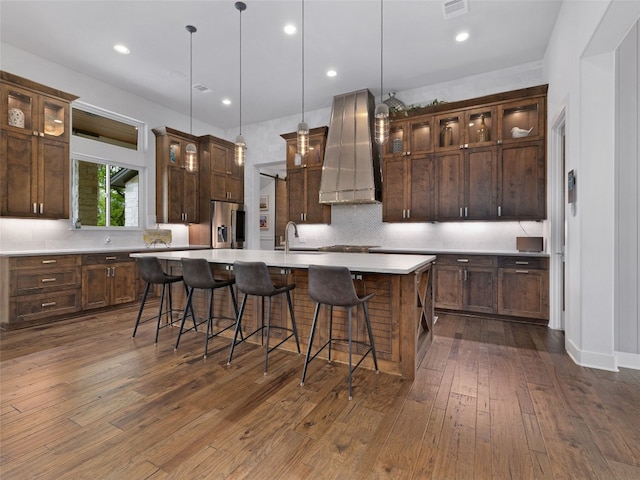 9806 Inca Ln, Austin, TX 78733 - kitchen featuring appliances with stainless steel finishes, range hood, a large island with sink, backsplash, and light countertops