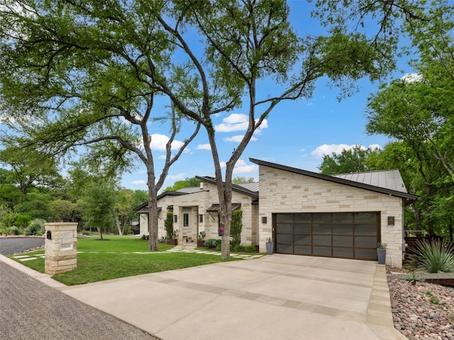 9806 Inca Ln, Austin, TX 78733 - modern home with stone siding, an attached garage, a front lawn, driveway, and a standing seam roof