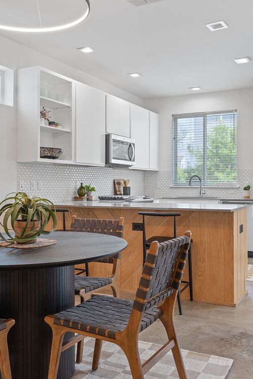 705 N Bluff Dr Unit 14, Austin, TX 78745 - kitchen featuring stainless steel microwave, backsplash, white cabinets, open shelves, and light countertops