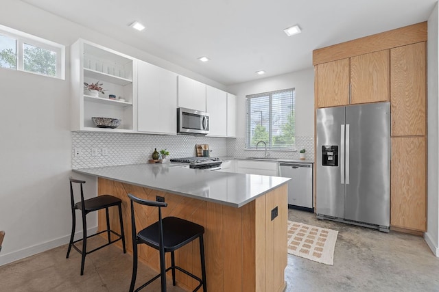 705 N Bluff Dr Unit 14, Austin, TX 78745 - kitchen featuring stainless steel appliances, a peninsula, tasteful backsplash, open shelves, and a breakfast bar area