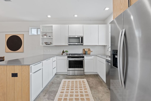 705 N Bluff Dr Unit 14, Austin, TX 78745 - kitchen featuring appliances with stainless steel finishes, a peninsula, open shelves, concrete floors, and decorative backsplash