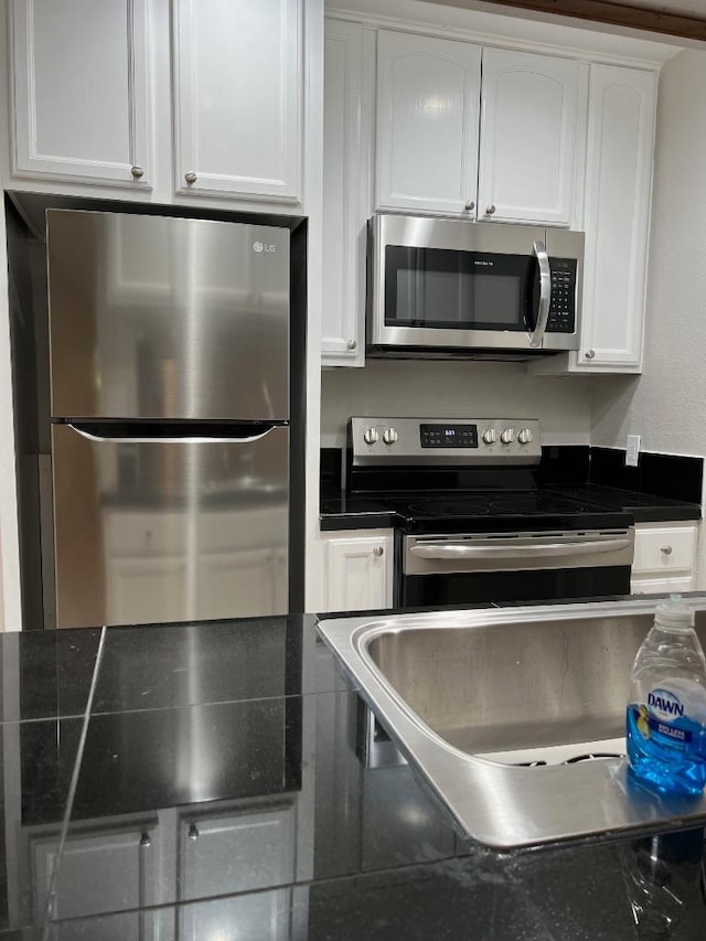 kitchen with dark countertops, white cabinetry, and appliances with stainless steel finishes