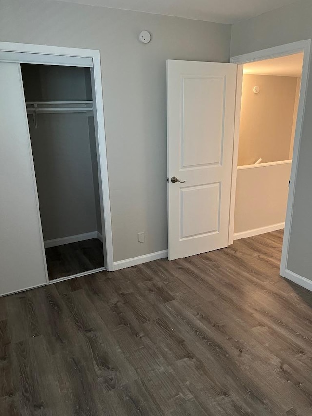 unfurnished bedroom with baseboards, wood finished floors, and a closet