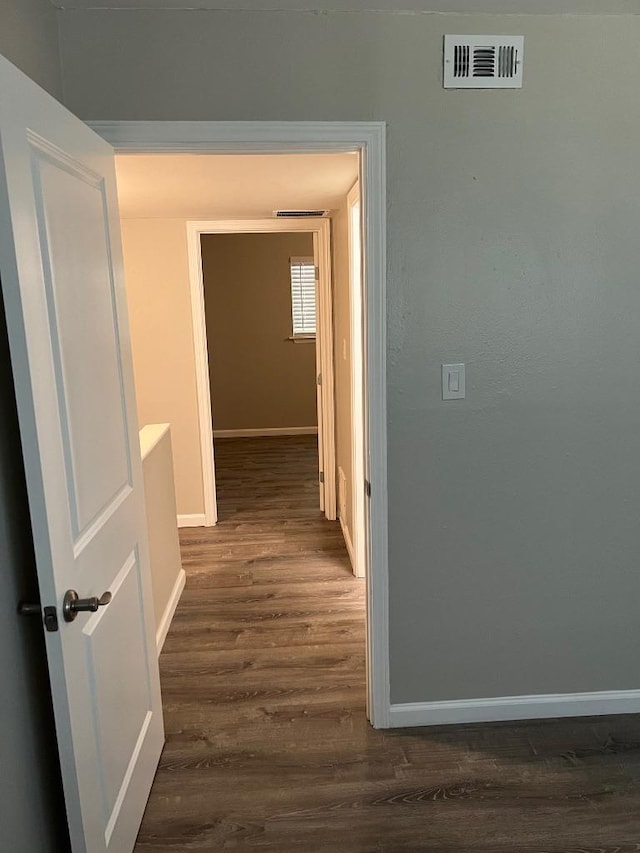 hallway with baseboards, dark wood-style flooring, and visible vents