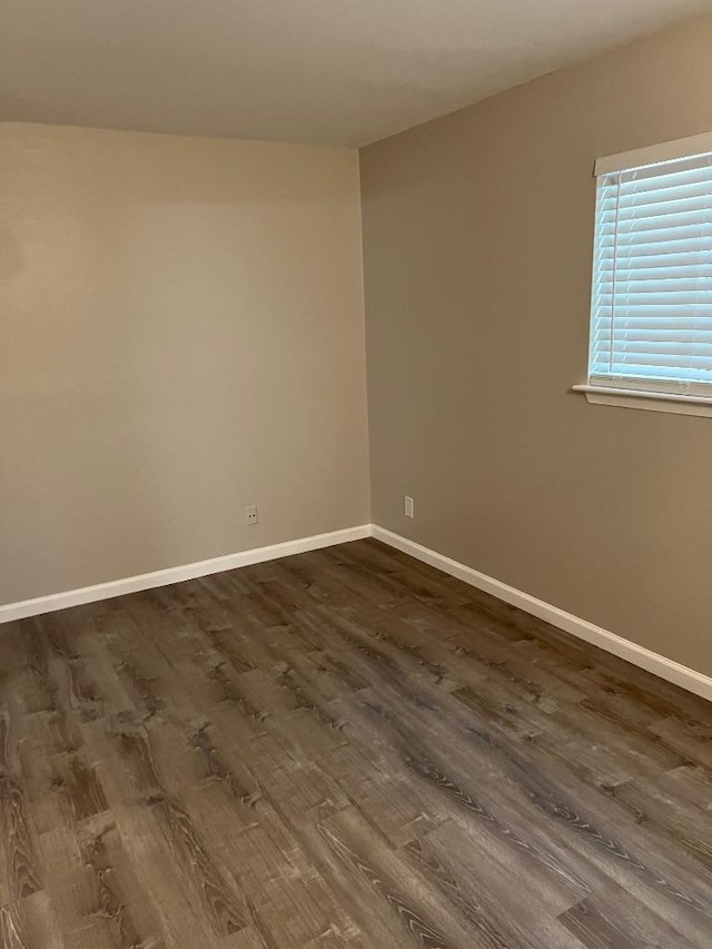 spare room with dark wood finished floors and baseboards