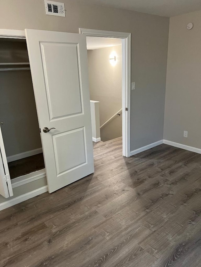 unfurnished bedroom featuring wood finished floors, visible vents, and baseboards