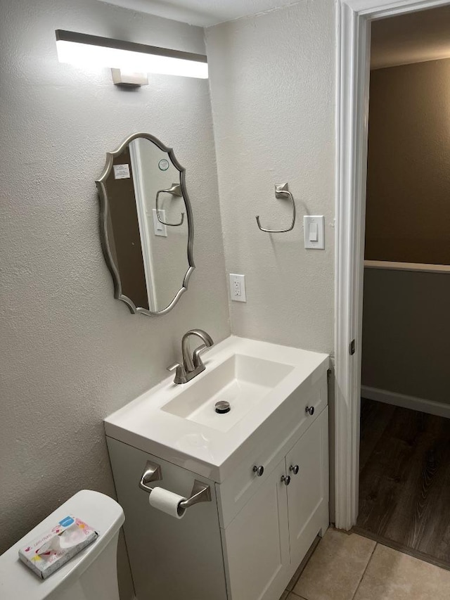 half bath featuring tile patterned floors, vanity, and toilet