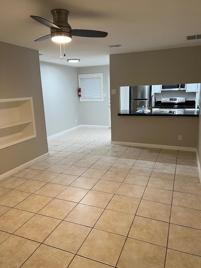 empty room with baseboards, a ceiling fan, a sink, and visible vents