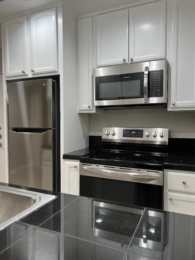 kitchen with white cabinets, dark countertops, and appliances with stainless steel finishes