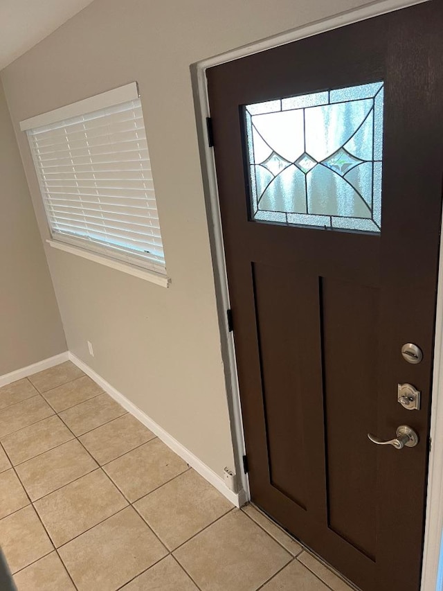 foyer entrance featuring light tile patterned flooring and baseboards