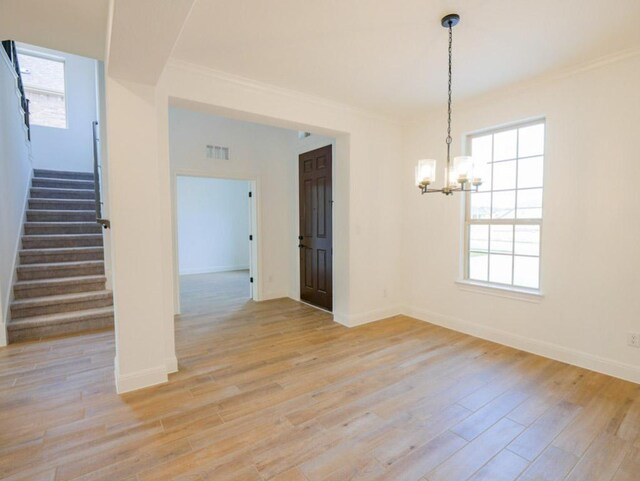 1705 Cayuga St, Leander, TX 78641 - spare room with stairs, a chandelier, light wood-style floors, crown molding, and healthy amount of natural light