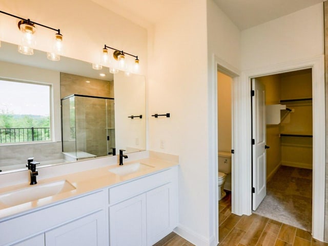 1705 Cayuga St, Leander, TX 78641 - full bathroom with a shower stall, a spacious closet, toilet, wood tiled floors, and double vanity